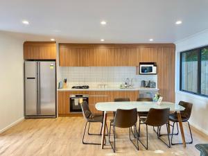 uma cozinha com uma mesa e cadeiras e um frigorífico em NO PARTY ALLOWED, Entire Brand New 3 bedroom townhouse, free unlimited fibre wifi and free parking em Wellington