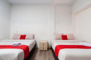 Cette chambre comprend 2 lits avec des murs blancs et des oreillers rouges. dans l'établissement RedDoorz At Jalan Asia Medan, à Medan