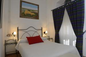 a bedroom with a white bed with a red pillow at Casa Rural Las Cadenas del Cananeo in Arcos de la Frontera