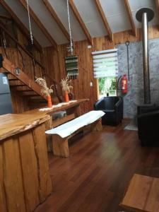 sala de estar con banco y mesa en Agradable Cabaña inserta en bosque nativo, en Pucón