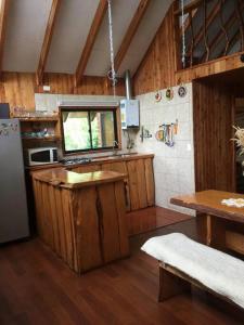 cocina con armarios de madera, nevera y mesa en Agradable Cabaña inserta en bosque nativo en Pucón