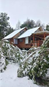 a log cabin with snow on top of it at Agradable Cabaña inserta en bosque nativo in Pucón +10 photos