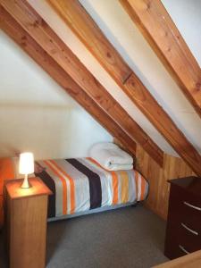 Dormitorio pequeño con cama en el ático en Agradable Cabaña inserta en bosque nativo, en Pucón
