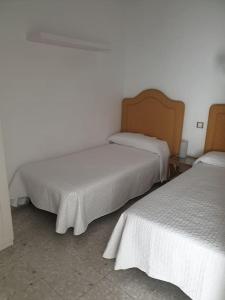 two beds in a room with white walls at Fantástico duplex en el centro de Osuna in Osuna