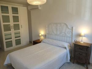 a bedroom with a white bed with two tables and two lamps at Fantástico duplex en el centro de Osuna in Osuna