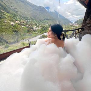 uma mulher sentada numa banheira de nuvens com vista em Aldea Real Eco Friendly em Baños