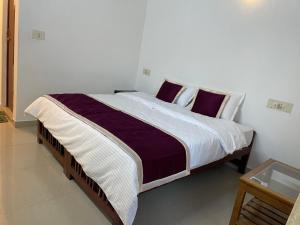 1 dormitorio con 1 cama grande con sábanas blancas y moradas en Wild Valley Club, en Masinagudi