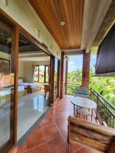 a room with a balcony with a bed and a table at BUDA AMITABA in Ubud