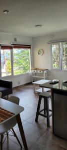 uma sala de estar com mesas, cadeiras e janelas em Lalúan departamento temporario em Ushuaia