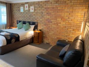 a bedroom with a bed and a couch and a brick wall at City View Motel in Warwick