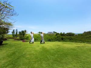 two people walking in a field of grass at Sungai Tinggi Beach Villa by Elite Havens in Canggu