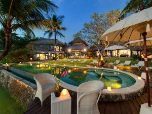 una piscina en un complejo con sillas y mesas en Sungai Tinggi Beach Villa by Elite Havens, en Canggu