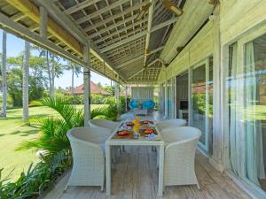 a porch with a table and chairs on it at Sungai Tinggi Beach Villa by Elite Havens in Canggu