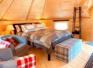 ein Schlafzimmer mit einem Bett und einem Stuhl in einer Hütte in der Unterkunft Seal Cove Cabin - Luxury Glamping in Cairndow
