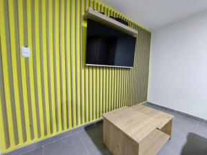 a room with a green wall with a tv and a bench at Tranquilo Apartamento Central Cerca a la Playa Puerto Colombia in Puerto Colombia