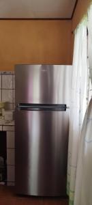 a stainless steel refrigerator in a kitchen next to a curtain at Casa Lora, camino a las playas. in Puerto Jiménez