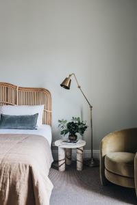 a bedroom with a bed and a lamp and a chair at Mittagong Hotel in Mittagong