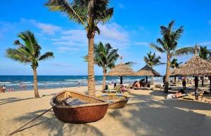 a beach with palm trees and a boat on the sand at Baphu Beachwalk Apartment - 5 min walk to My Khe beach in Da Nang