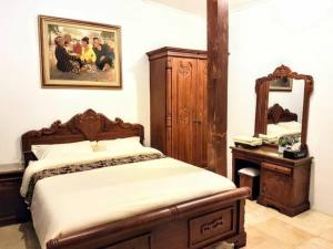 nDalem Julang Bogor - Javanese House 2BR في بوغور: غرفة نوم بسرير وخزانة ومرآة