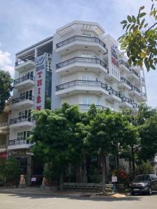 un grand bâtiment blanc avec des arbres devant lui dans l'établissement Thien Ha Hotel, à Thu Dau Mot