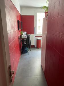 a red kitchen with a table and a red wall at Chambre meublée prune boulevard Joseph Vallier in Grenoble