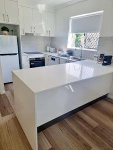 una cocina blanca con una gran encimera blanca en Stunning 2 BR, 2 Bathroom Beachfront Apartment Close To Everything!, en Hervey Bay