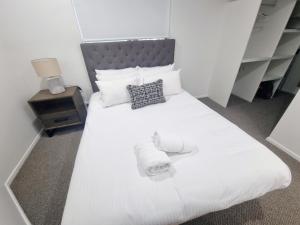 1 dormitorio con cama blanca y cabecero gris en Stunning 2 BR, 2 Bathroom Beachfront Apartment Close To Everything! en Hervey Bay