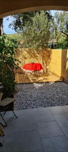 une terrasse avec une table rouge en face d'une clôture dans l'établissement Coquet Rez jardin plage parking wifi, à Saint-Mandrier-sur-Mer