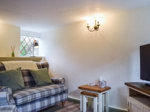 Drapers Cottage في Foxton: غرفة معيشة مع أريكة وتلفزيون