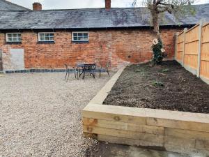 a brick building with a yard with a table and a tree at Drapers Cottage in Foxton