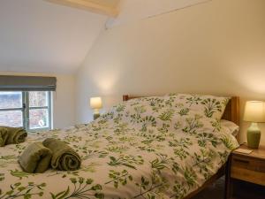 a bedroom with a bed with a green bedspread at Drapers Cottage in Foxton