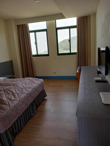 um quarto com uma cama, uma secretária e janelas em Lohas Seaview B&B em Beigan