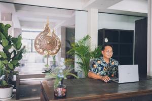 a man sitting at a table with a laptop computer at The Dale Pattaya Boutique and Spa in Pattaya South +38 photos