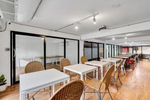 a row of tables and chairs in a room with windows at Chill Inn Bangkok in Bang Kapi