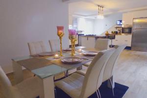 a dining room table with white chairs and a kitchen at Villa à bahia golf beach in Kasba Bou Hamira