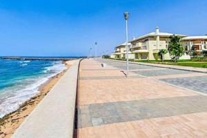 a walkway next to the beach with houses at Villa à bahia golf beach in Kasba Bou Hamira