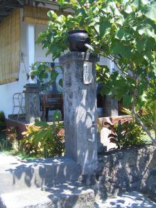 un pilar de piedra con un árbol delante de una casa en Alur Beach Homestay, en Amed
