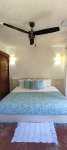 una camera con un grande letto e un ventilatore a soffitto di A Son de Mar - Playa Las Gatas acceso por mar a Zihuatanejo