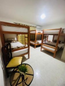a room with three bunk beds and a table at Hostal Casa San Pedro in Santa Marta