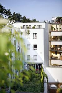 ein weißes Gebäude mit einem Garten davor in der Unterkunft Ambassador Self Check-in Hotel in Luzern