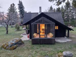 a small black house with a window in a field at Puise saunahouse and outdoor kitchen at Matsalu Nature Park in Puise