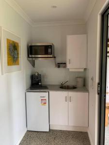 a small kitchen with white cabinets and a microwave at Fern3BnB in Denmark