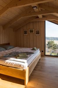 Bett in einem Holzzimmer mit einem großen Fenster in der Unterkunft Apartmán Nežichov 2 U Polocka in Toužim