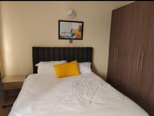 a bed with a yellow pillow on top of it at Spacious and Serene 1 bedroom apartments with a lake view and town view in Nakuru