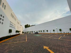 ein großes weißes Gebäude mit Parkplatz in der Unterkunft HOTEL MARQUES DEL PEÑON in Mexiko-Stadt
