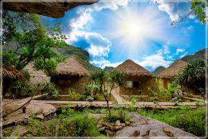 a group of huts with mountains in the background at Hang Mua Eco Garden in Xuân Sơn