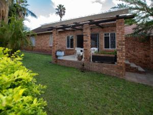 a brick house with a patio and a yard at Dew Drop Inn in Nelspruit