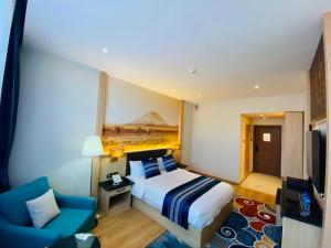 ein Hotelzimmer mit einem Bett und einem blauen Stuhl in der Unterkunft Mazaalai Hotel 