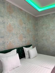 a bed with white pillows in a bedroom at Hotel Guest House GOLDEN DEGREZ in Bukhara