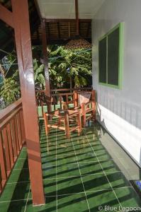 a porch with chairs and a table on a house at Blue Lagoon Guest house for Backpakers in Puerto Galera